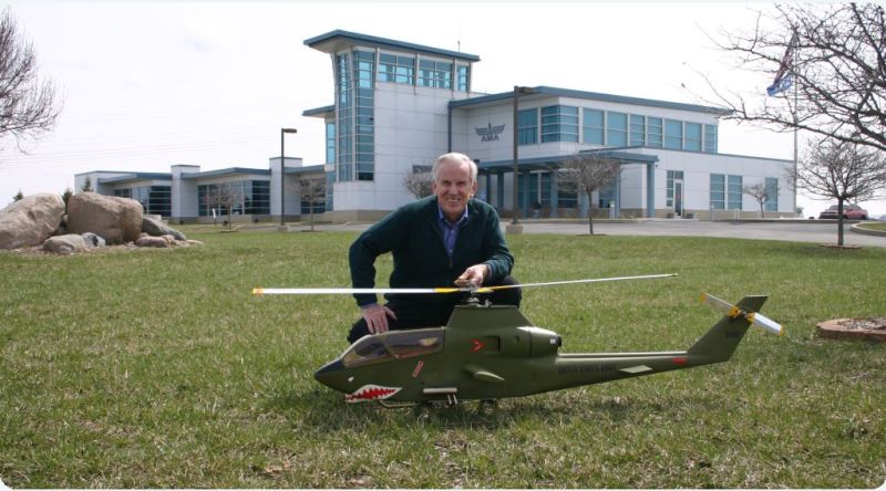 Horace G. Hagen poses in front of the AMA Headquarters building with his AH-1G Bell Huey Cobra model helicopter right before donating it to the National Model Aviation Museum.